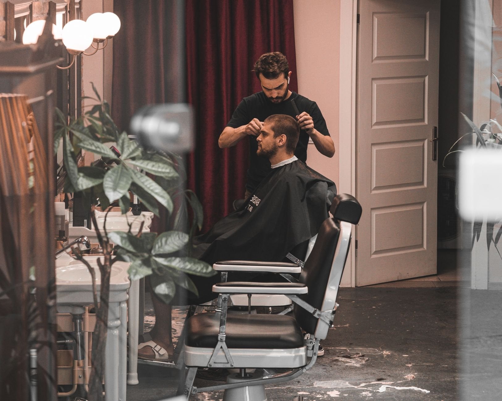 Barber styling a man's hair in a chic, modern salon interior, showcasing professional hairdressing skills.